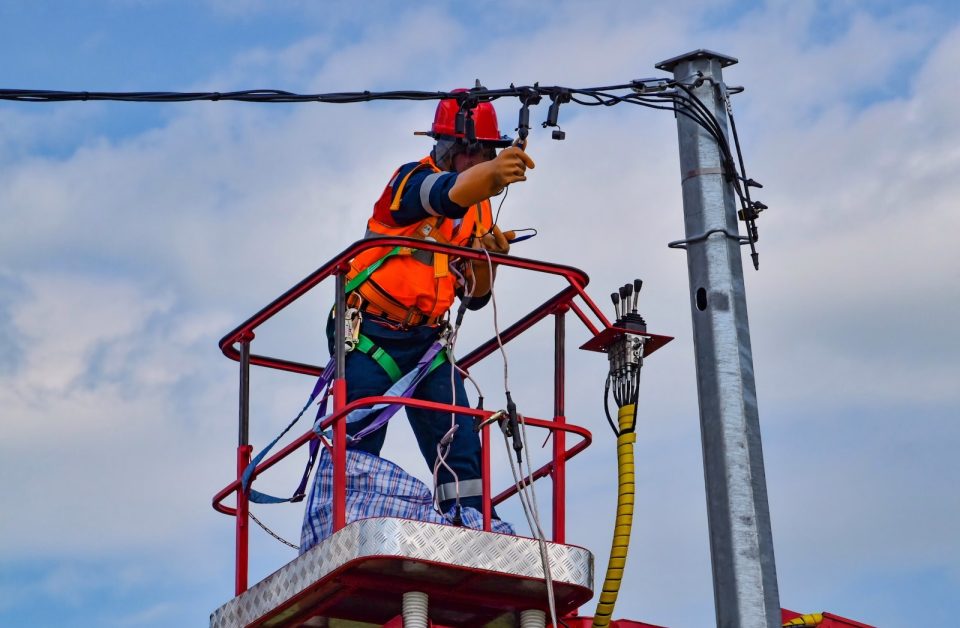 2 men in orange safety helmet riding on red and yellow cable car during daytime