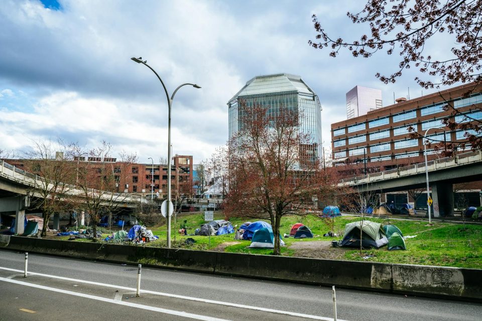 Colorful tents set up in a green area of downtown Portland, Oregon, highlight urban social issues.