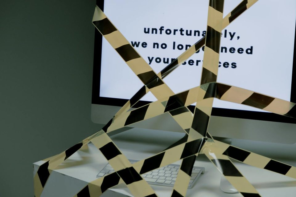 A computer screen taped and displaying a termination message, symbolizing unemployment.