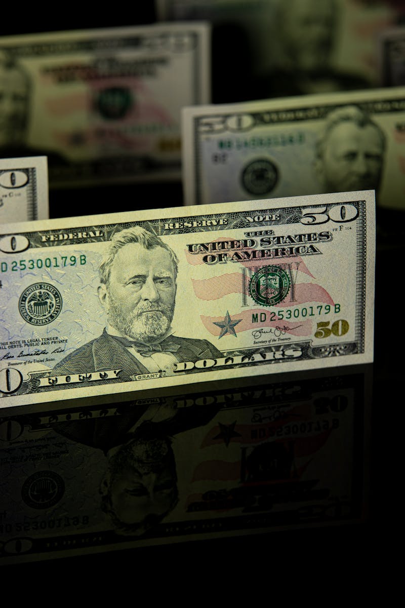 US fifty dollar bills with reflection on dark background symbolizing wealth and finance.