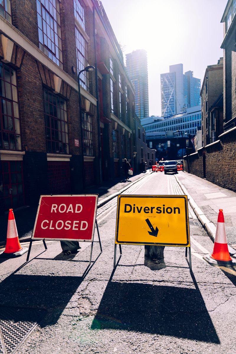 two traffic cones in between road closed and diversion road signs viewing buildings during daytime