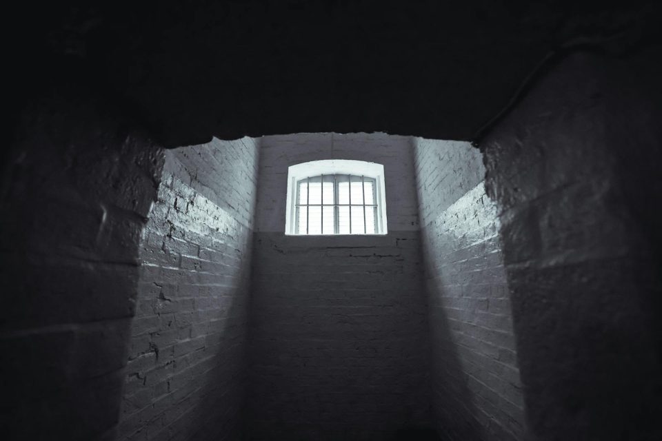 Moody shot of an abandoned prison cell in Hong Kong with dim lighting and shadowy walls.