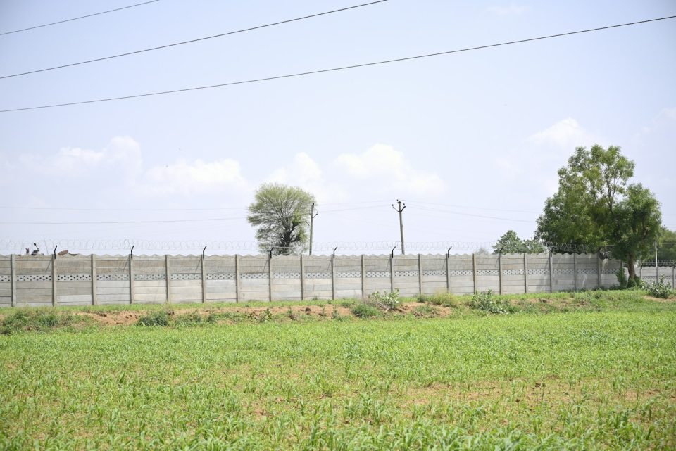 A field with a fence and trees in the background