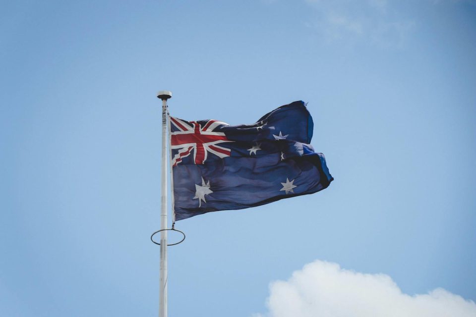 Australian national flag waving on a flagpole against a clear blue sky in Perth.