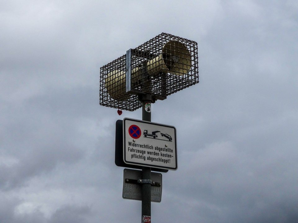 Outdoor siren mounted on a pole with signs