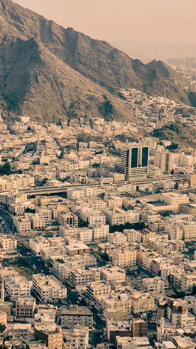 A stunning aerial view of Makkah's urban landscape with mountains in the background under a warm light.
