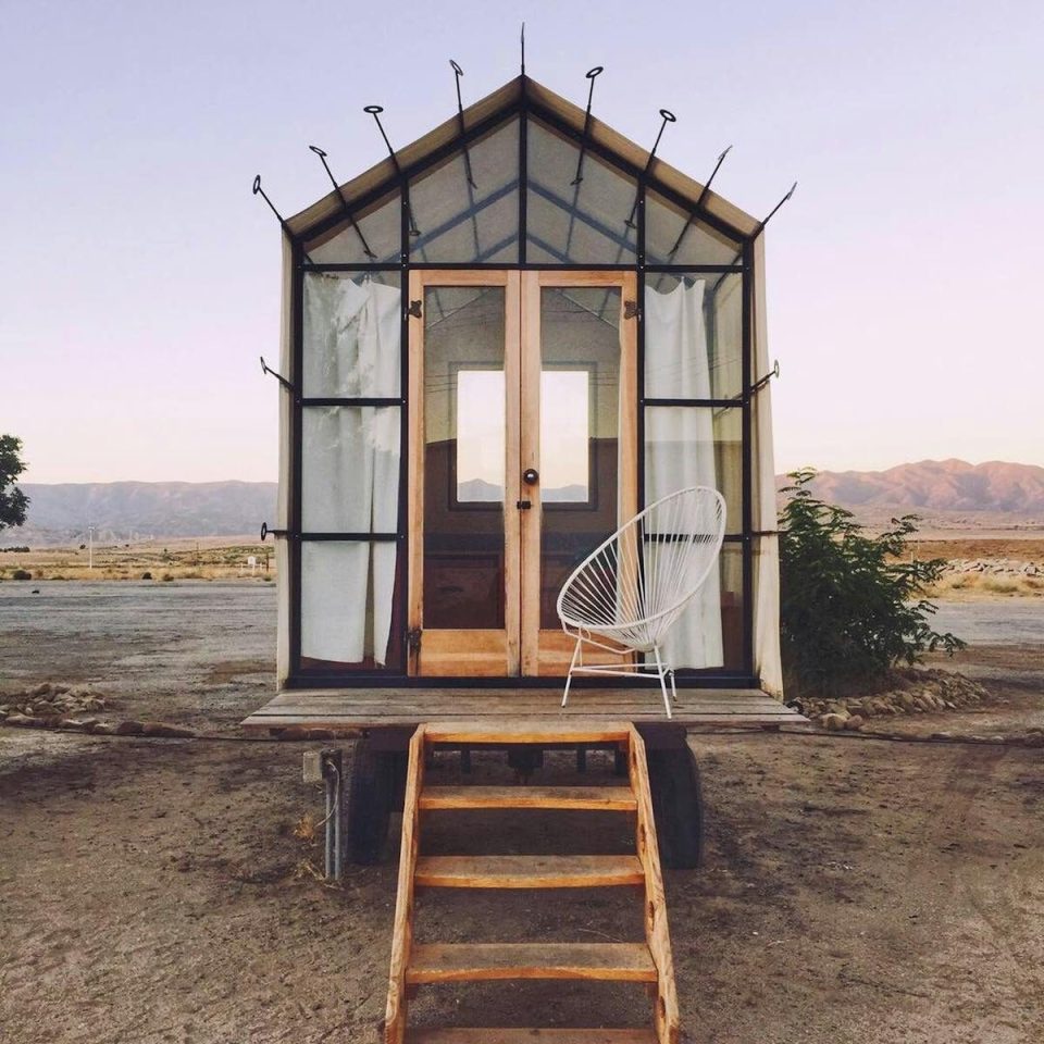 Cozy tiny house with chair in New Cuyama desert setting.