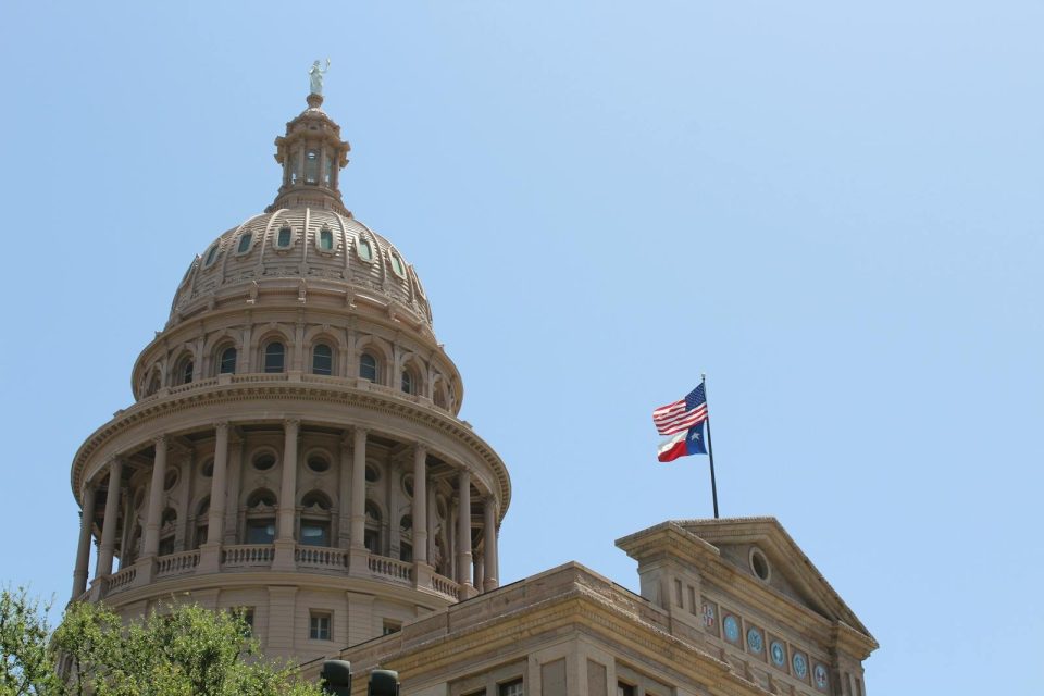 Low angle view of the Texas State Capitol dome and flags in Austin, Texas.