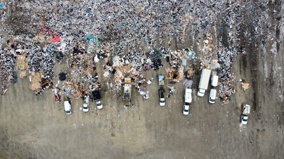 Aerial view of a large landfill with garbage trucks.