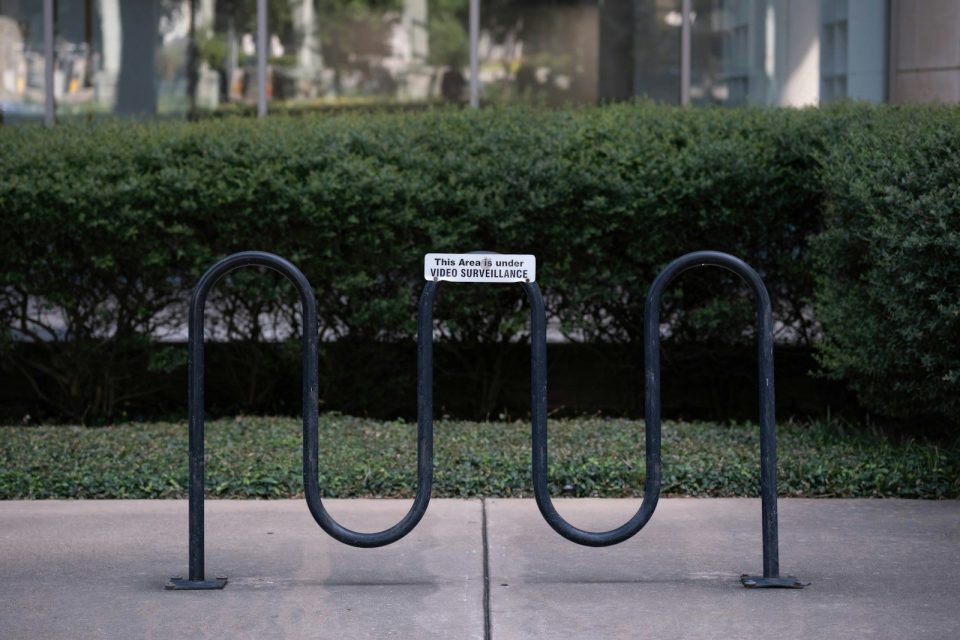 Empty black bicycle rack in front of bushes