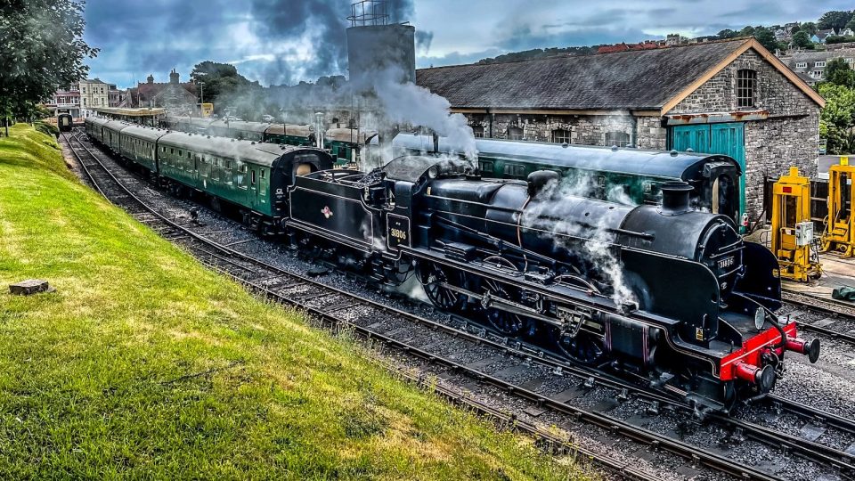 A train traveling down train tracks next to a lush green field