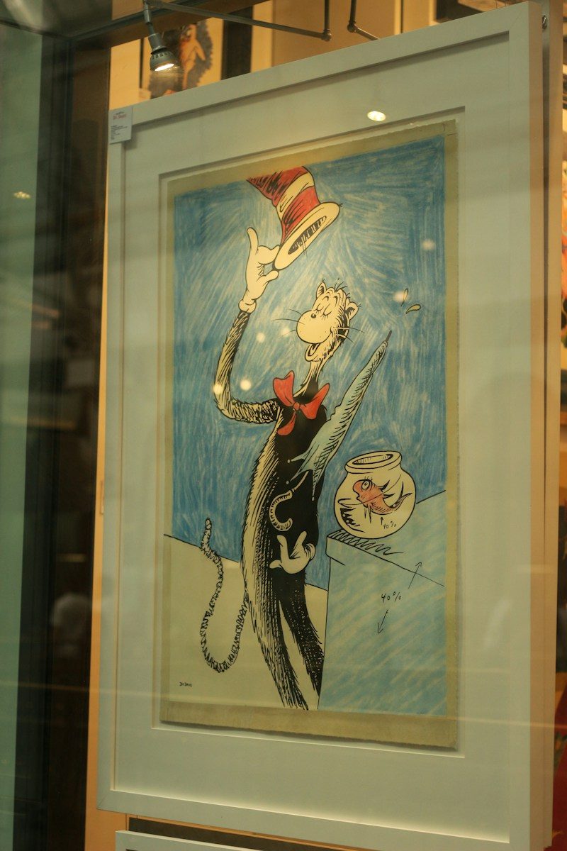 The cat in the hat balancing a red striped hat