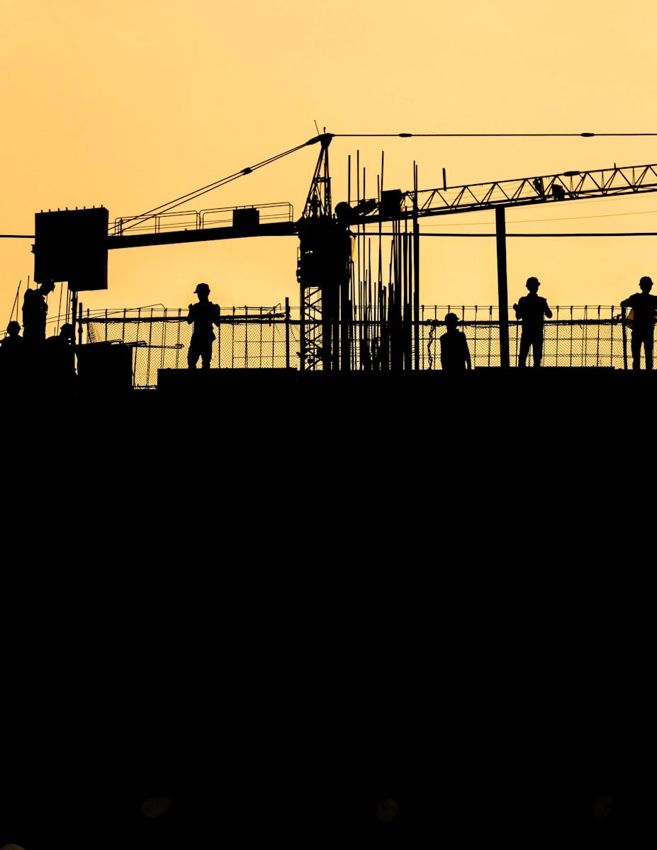 silhouetted construction workers at sunset