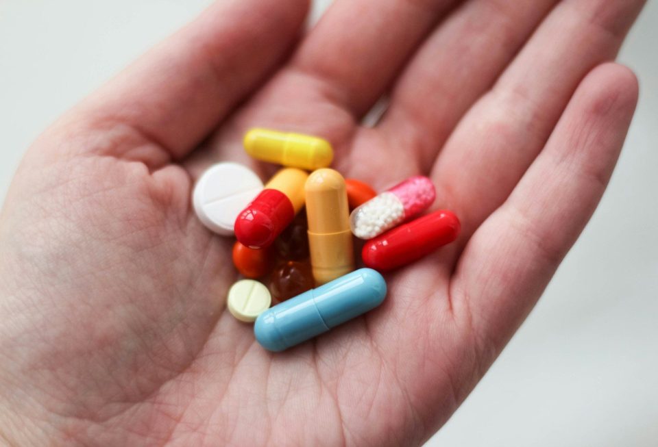 A handful of colorful pills and capsules held in an open palm